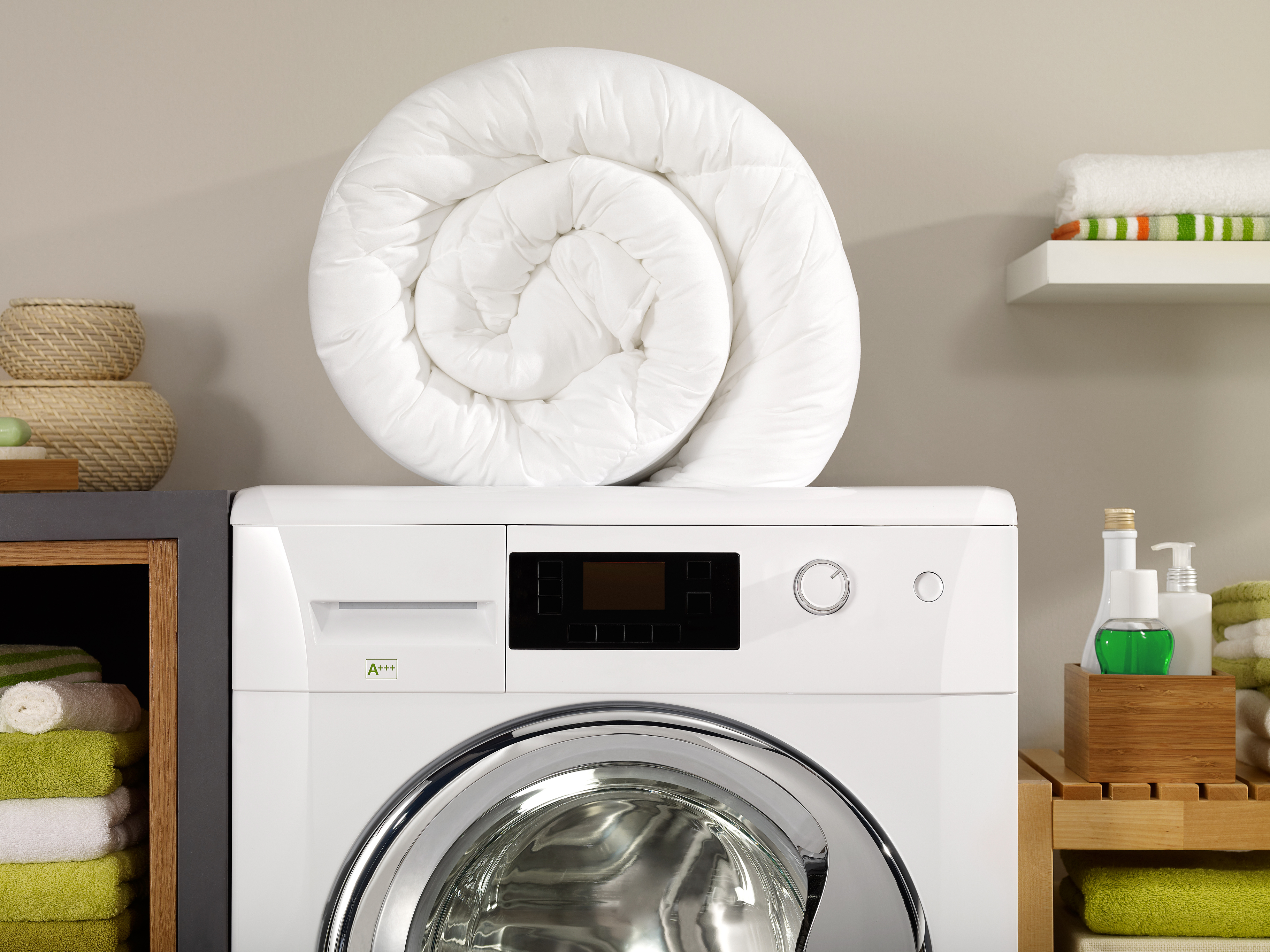 A comforter on top of a front load washer.